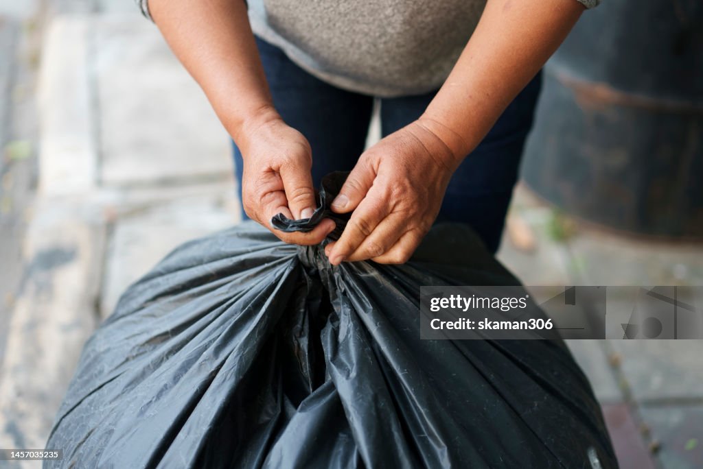Selective focus hands try to tie a trash bag for recycle