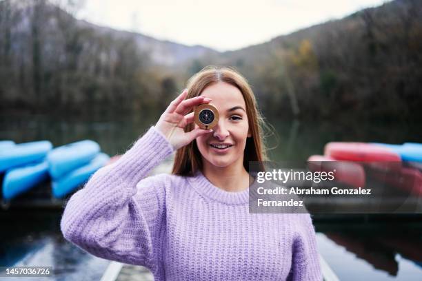 portrait of a woman in a purple sweater holding a compass. - giving directions stock pictures, royalty-free photos & images