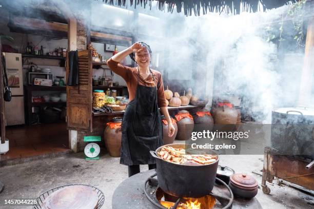 young smiling vietnamese female chef cooking in open kitchen in restaurant - hot vietnamese women stock pictures, royalty-free photos & images