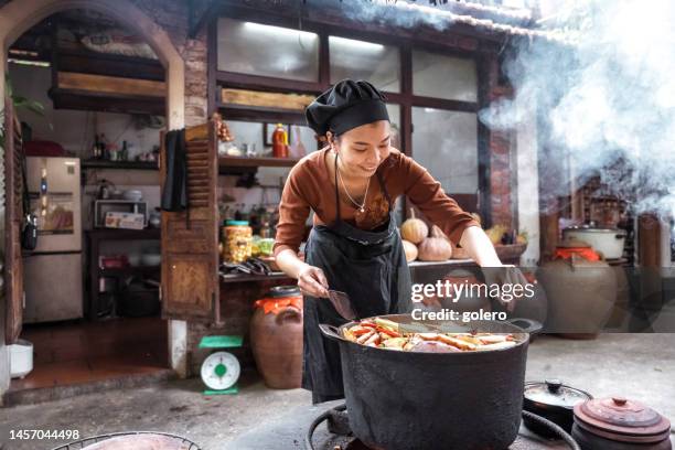 young vietnamese female chef cooking on open fire in steaming kitchen - hot vietnamese women stock pictures, royalty-free photos & images