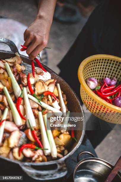 female hand putting chillies in huge cooking pan with fish and vegetables - hot vietnamese women stock pictures, royalty-free photos & images