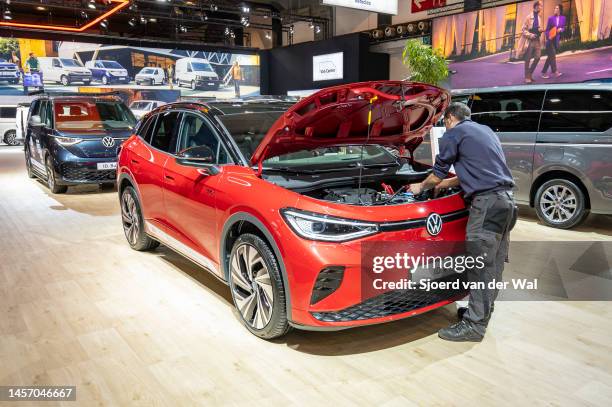 Volkswagen ID.4 GTX full electric SUV car with a technician chekcing the electronics under the hood on display at Brussels Expo on January 13, 2023...