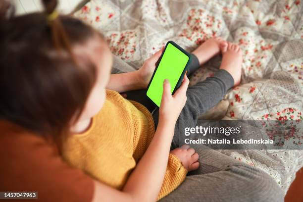 girl child teenager and younger toddler together watching look at smartphone. - children screen stock-fotos und bilder