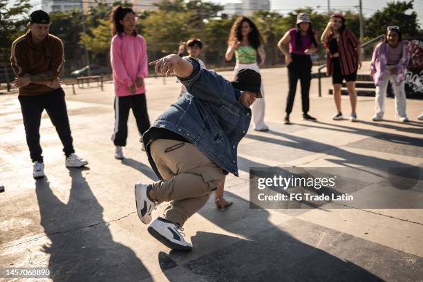 young man breakdancing during street party with her friends outdoors - break dance city stock pictures, royalty-free photos & images