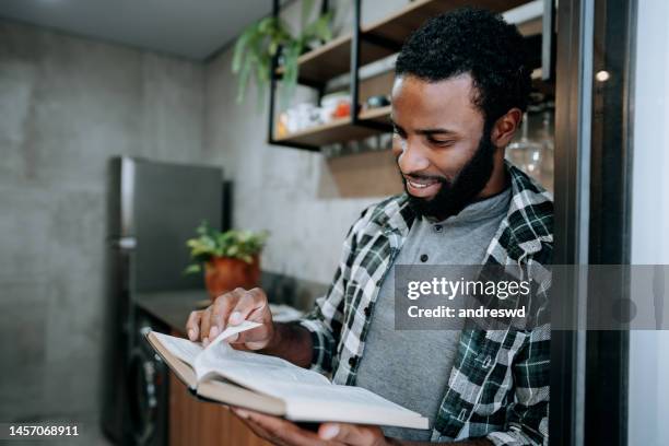 man standing reading the bible at home - worshipper bildbanksfoton och bilder