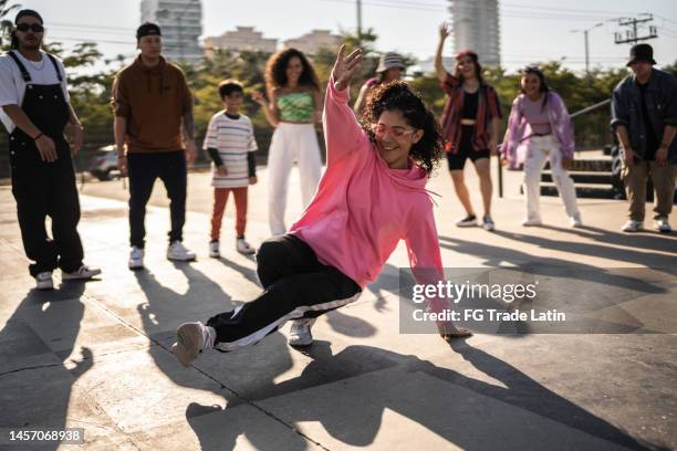 young woman breakdancing during street party with her friends outdoors - hip hop stockfoto's en -beelden