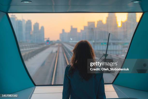 woman traveling in dubai metro at sunset - dubai metro stockfoto's en -beelden