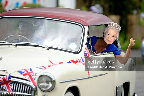 Reveller wears a Queen Elizabeth II mask as she leans out of a car window, during a countryside Diamond Jubilee street party on June 4, 2012 in...