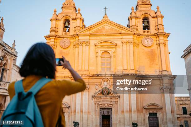 young female tourist taking a photo of st paul's cathedral  in malta - malta city stock pictures, royalty-free photos & images