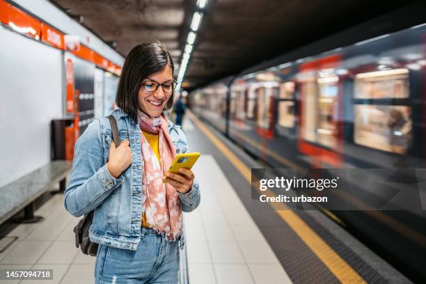 giovane donna che usa il telefono in una stazione della metropolitana - metropolitana foto e immagini stock