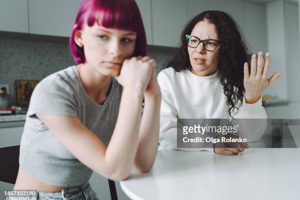single working mother and her teenage girl talking sadly in the kitchen - parent teen stock pictures, royalty-free photos & images