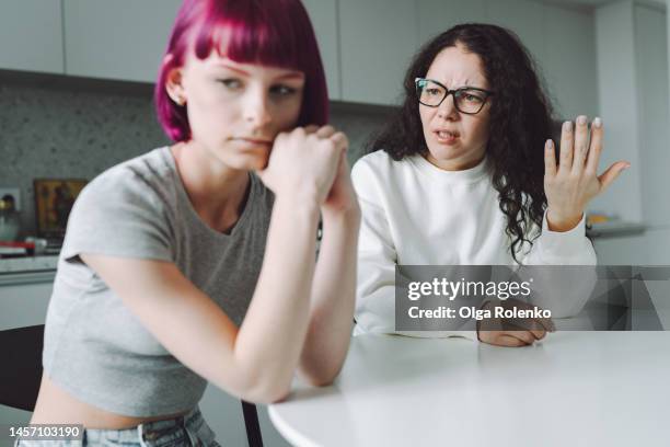 single working mother and her teenage girl talking sadly in the kitchen - arguing photos 個照片及圖片檔