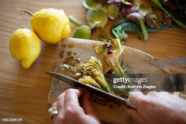 woman slicing fresh artichokes, close-up of hands - artichoke stock pictures, royalty-free photos & images