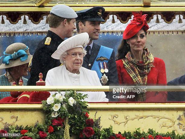In heavy rain, Prince Harry, Britain's Queen Elizabeth, Prince William and Catherine, Duchess of Cambridge, watch from onboard the royal barge...