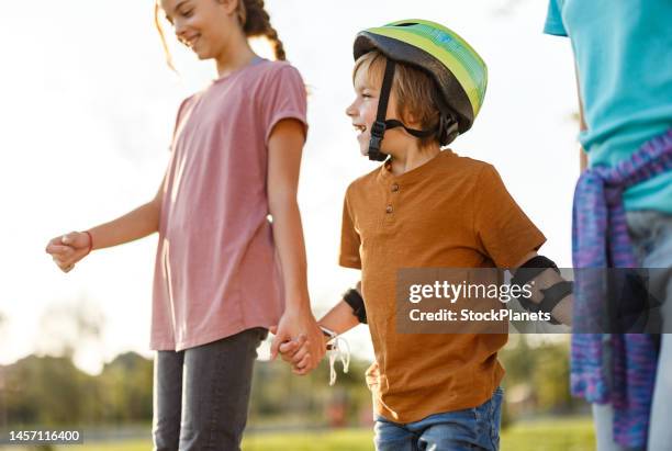 niños con patines tomados de la mano - patina fotografías e imágenes de stock