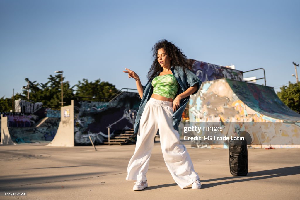 Mid adult woman dancing reggaeton at skateboard park
