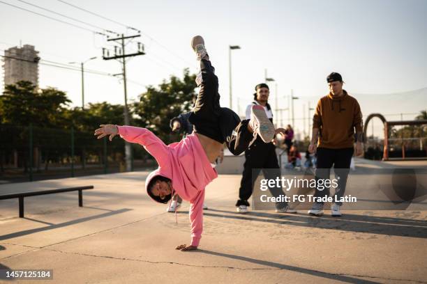 mujer joven bailando breakdance durante una fiesta callejera con sus amigos - hip hop fotografías e imágenes de stock