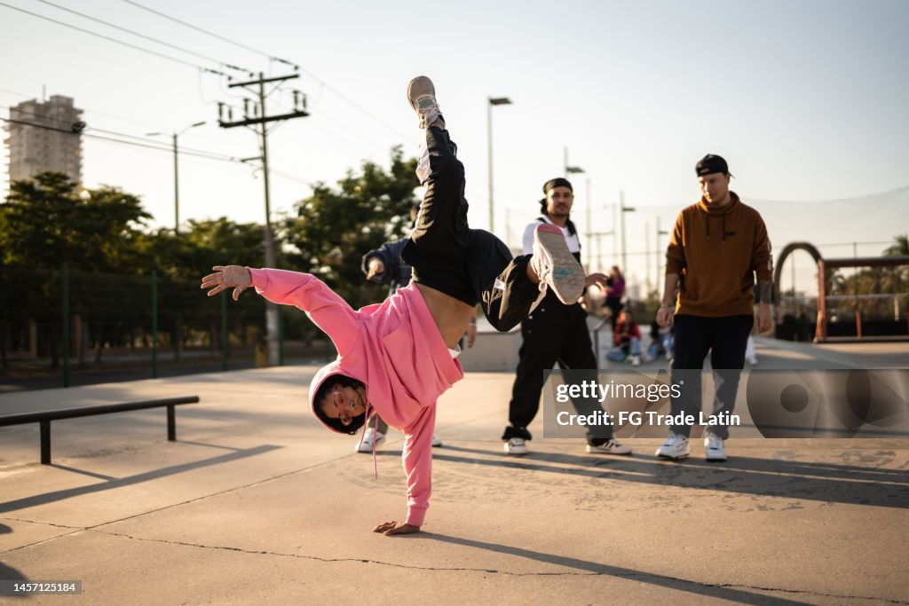 Young woman breakdancing during street party with his friends