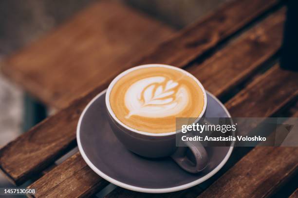 close-up photo of a cup of fresh specialty coffee with art. tasty cappuccino is on a wooden table. - coffee foam imagens e fotografias de stock