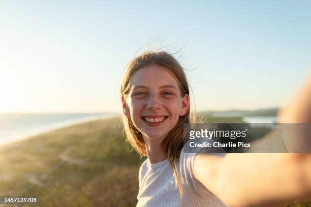 smiling young woman takes a selfie - self portrait photography stock pictures, royalty-free photos & images