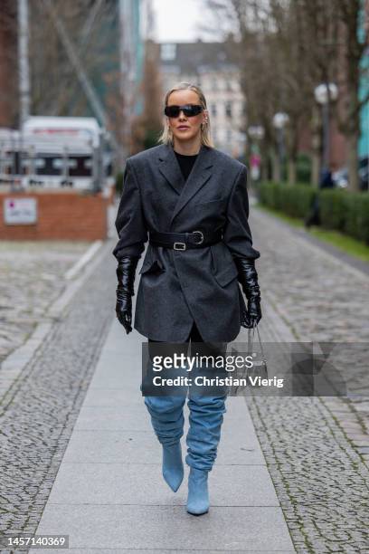 Tina Haase wears grey belted blazer, blue over knees denim boots, black gloves, silver bag during the Berlin Fashion Week AW23 on January 17, 2023 in...