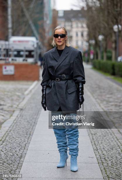 Tina Haase wears grey belted blazer, blue over knees denim boots, black gloves, silver bag during the Berlin Fashion Week AW23 on January 17, 2023 in...