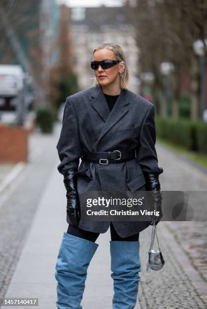 Tina Haase wears grey belted blazer, blue over knees denim boots, black gloves, silver bag during the Berlin Fashion Week AW23 on January 17, 2023 in...