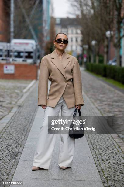 Anna Idriess wears beige tailored blazer, black bag, Celine sunglasses, creme white wide leg pants during the Berlin Fashion Week AW23 on January 17,...