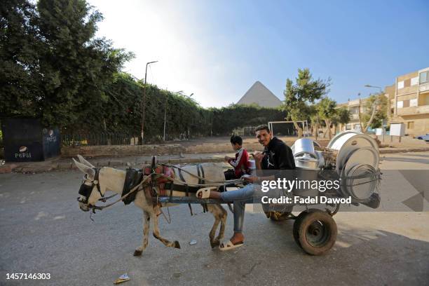 Man selling ammonia tools in a wooden cart and a donkey on January 17, 2023 in Nazlet El-Semman near the pyramids Giza, Egypt. The Egyptian pound...