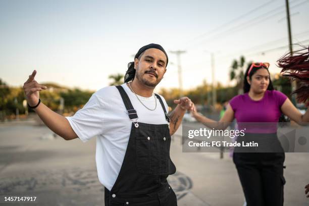 portrait d’un homme adulte dansant le hip hop avec ses amis au parc de planche à roulettes - gangsta rap photos et images de collection