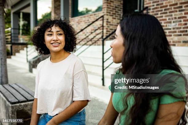 two women sitting on the bench and talking - friendship stock pictures, royalty-free photos & images