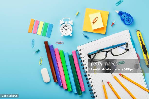 office supplies are on the blue table,for working with your own hands at home,romania - desk of student alarm clock books and pencils foto e immagini stock