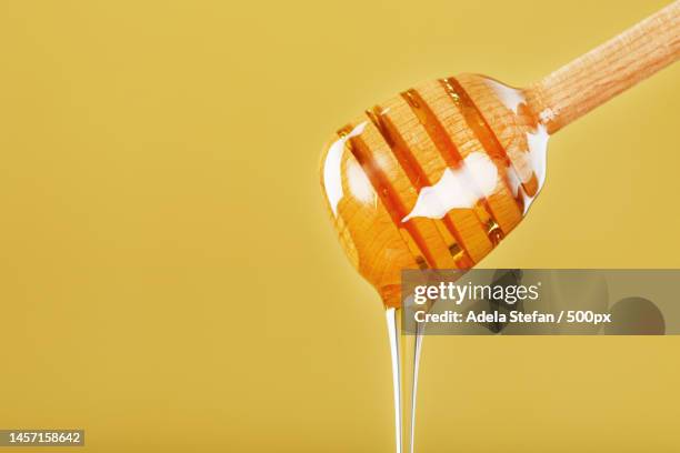 natural honey flows down from a honey bucket on a yellow background,romania - honey stockfoto's en -beelden