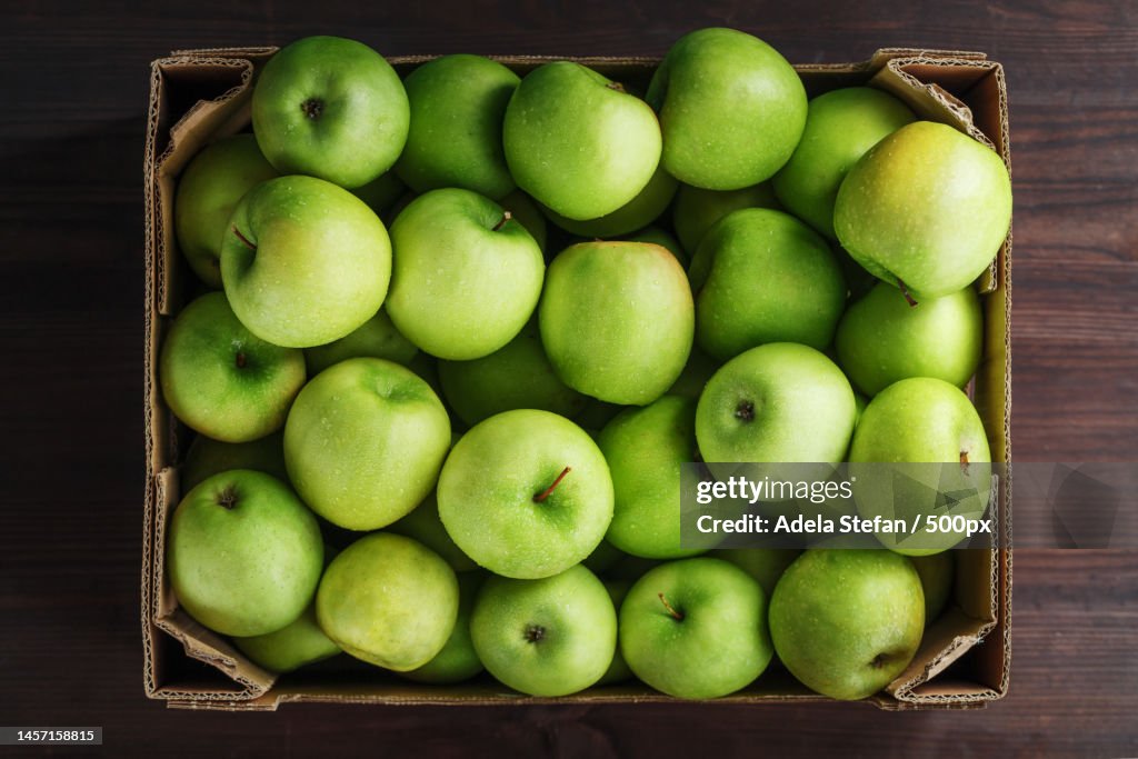 Ripe and juicy Green apples in a box on a wooden table,Romania