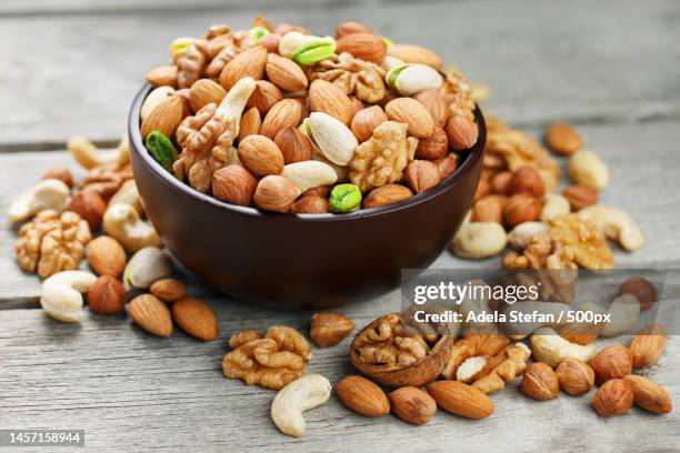 wooden bowl with mixed nuts on a wooden gray background walnut,pistachios,almonds,hazelnuts and,romania - nuss stock-fotos und bilder