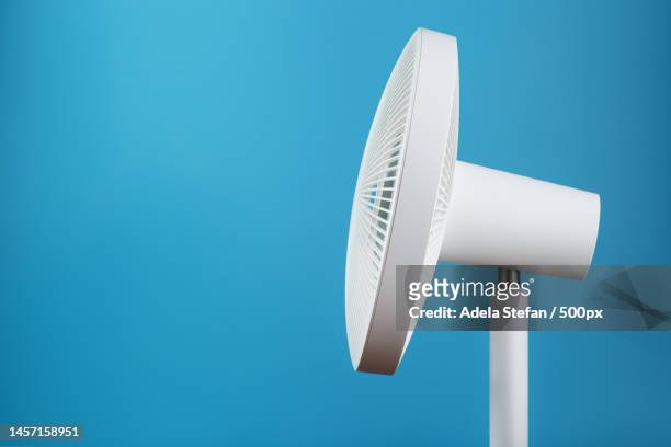 white modern electric fan for cooling the room on a blue background,romania - table fan stock pictures, royalty-free photos & images