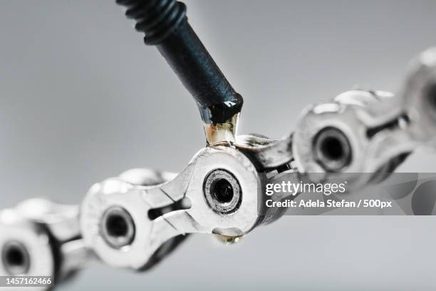 greasing a bicycle chain with a drop of golden oil close-up on a gray background,romania - grease stock pictures, royalty-free photos & images