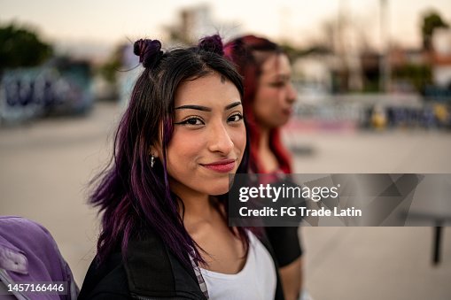 Portrait of young woman walking with her friends at skateboard park