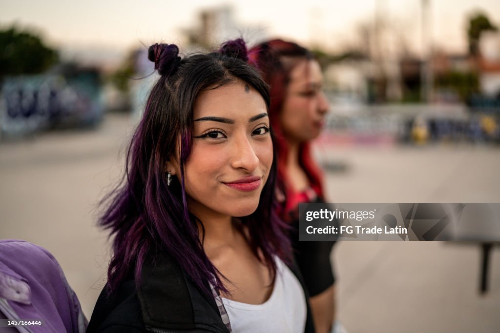 Portrait of young woman walking with her friends at skateboard park