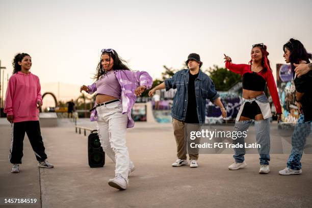 young woman dancing hip hop during street party with her friends - broken skateboard stockfoto's en -beelden