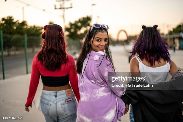 portrait of young woman walking with her friends at skateboard park - skatepark bildbanksfoton och bilder