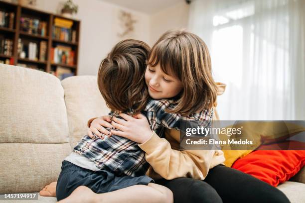 the little brother hugs his sister and laughs. support and time with family - kins fotografías e imágenes de stock