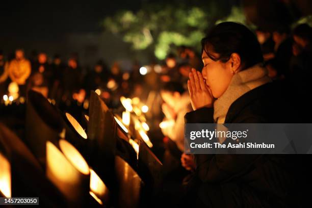 People pray for the victims in front of the candle-lit lanterns on the 28th anniversary of the Great Hanshin Earthquake on January 17, 2023 in Kobe,...