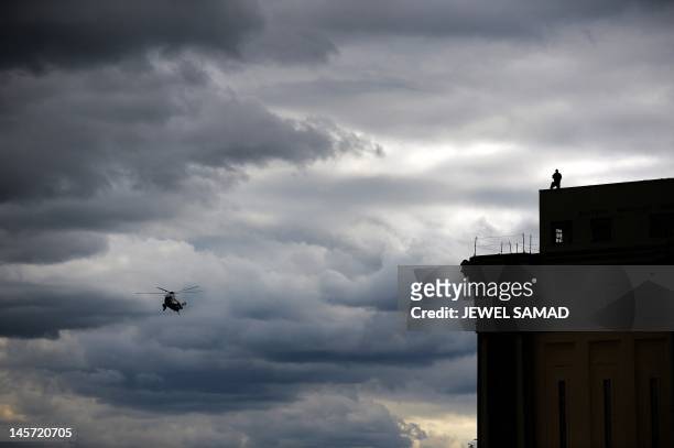 Secret Service personnel mans his position on top of a building as Marine One helicopter with US President Barack Obama on board prepares to land on...