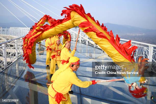 Villagers perform dragon dance on a glass skywalk alongside a cliff to greet Chinese New Year, the Year of the Rabbit, at the Shiniuzhai National...