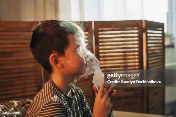 poor boy have a problem with chest coughing holding inhaler mask, child using the volumtic for breathing treatment, kid having asthma allergy using the asthma inhaler, healthcare and medicine concept - nebulizador fotografías e imágenes de stock