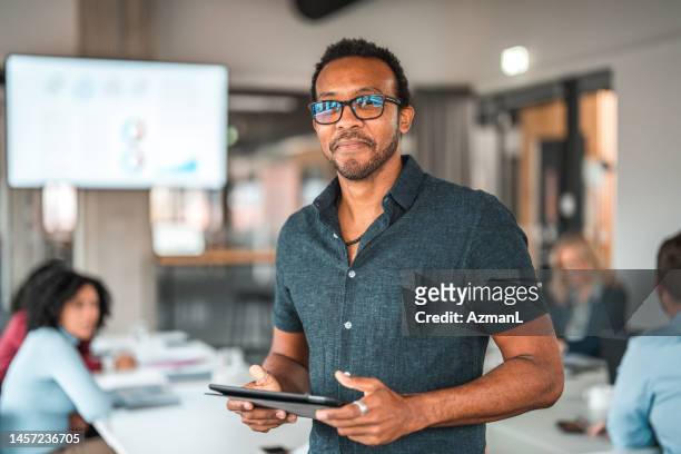 businessman using a digital tablet and looking at camera - marketing director stock pictures, royalty-free photos & images