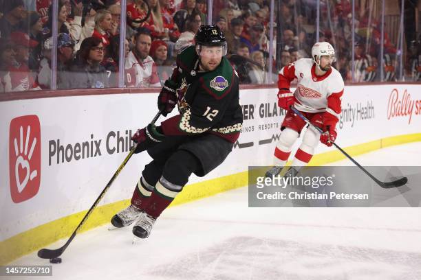 Nick Ritchie of the Arizona Coyotes skates with the puck ahead of Dylan Larkin of the Detroit Red Wings during the second period of the NHL game at...