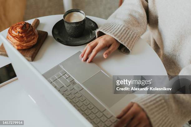 female using laptop at a cafe. young woman sitting at a table with a cup of coffee and fresh croissants bakery. lifestyle - kazakhstan food stock pictures, royalty-free photos & images