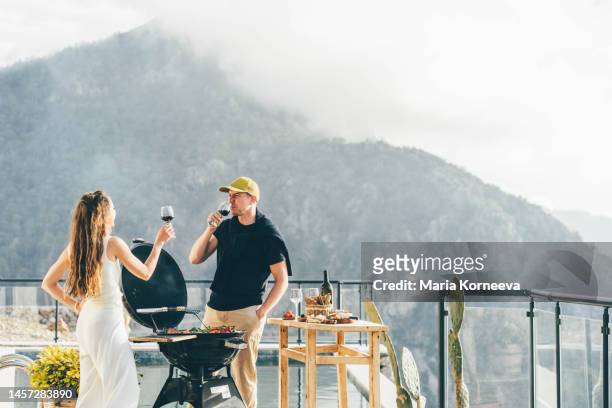 couple having a barbecue outdoors. - couple grilling stock-fotos und bilder